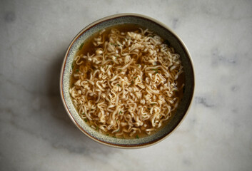 round plate with prepared instant noodles and black spoon close-up top view. ready ramen noodles. cooked ramen broth	