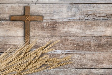 Wood cross and golden wheat on desk