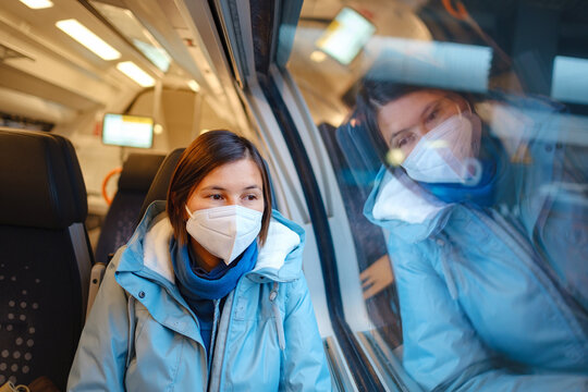 Asian Woman in blue jacket and protective mask looking out of train window in winter day. Lifestyle concept.