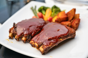 Grilled pork ribs topped with special marinade bbq sauce, french fries and vegetable