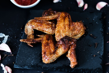 
Grilled spicy chicken wings with ketchup, on a dark background