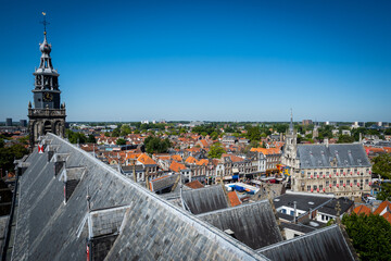 Dutch cityscape view from gothic Saint Johns Church Gouda Netherlands of rooftops and townhall city hall Stadhuis on a sunny summer day. impressive architecture makes prominent attraction for tourism - 560646728