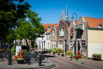 A typical Dutch street in Gouda in the Netherlands on a sunny summer day. Houses demonstrate local...