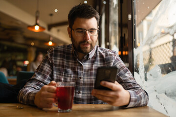 Bearded Man sitting alone at cafe or restaurant use smart phone