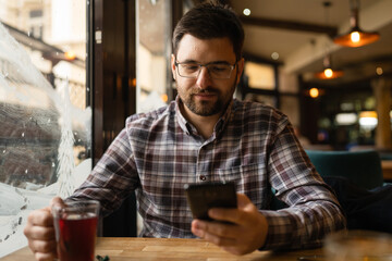 Bearded Man sitting alone at cafe or restaurant use smart phone