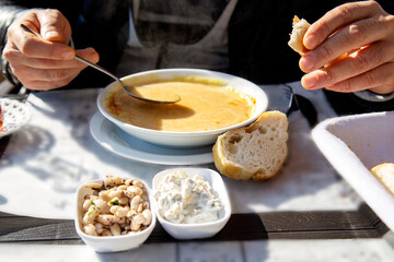 Person eating lentil soup with white bread 