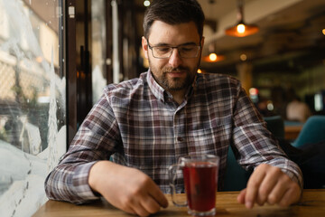 Bearded Man sitting alone at cafe or restaurant with glass cup of tea