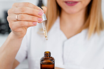 Vitamins for the restoration and renewal of the face. Girl applies face serum to her face with...