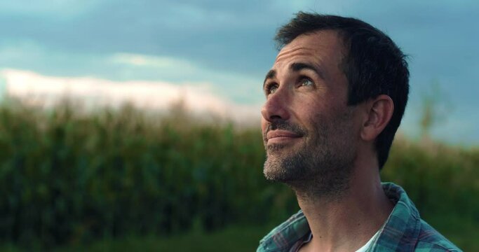 Happy Man Smiling and Looking Around in a Green Field of Corn. Handsome Middle-aged Male Farmer Enjoying the View, Thankful for the Good Weather, Hopeful for the Future of his Crops and Business