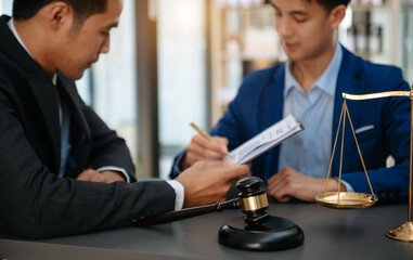 justice and law concept.law theme  wooden desk, books, balance. Male judge in a courtroom the gavel,working with digital tablet computer on table