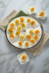 Gefüllte teuflische russische Eier mit Dill und orange Keta Lachs und gelb Saibling Kaviar auf Eierteller, Serviette grün, Silber Teller und Marmor Hintergrund hell