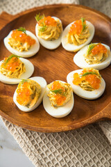 Gefüllte teuflische russische Eier mit Dill und orange Keta Lachs Kaviar auf Holz Eierteller und Serviette 