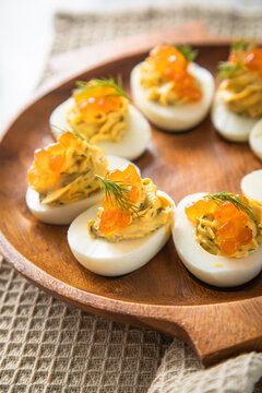 Gefüllte teuflische russische Eier mit Dill und orange Keta Lachs Kaviar auf Holz Eierteller und Serviette 