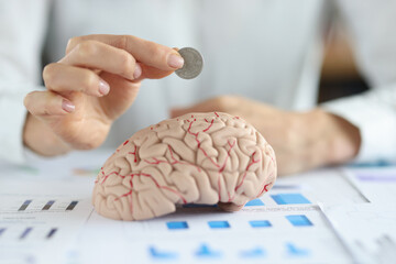 Businesswoman put coin into human brain model
