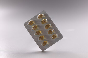 Fish oil Omega 3 tablets in blister pack with capsules on gray background