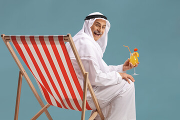 Arab man sitting on a beach chair with a cocktail and smiling