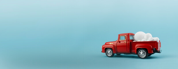 Toy red car on a blue background. There are big white balloons in the red truck. Christmas background with copy space. Christmas concept. High quality photo