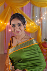 Beautiful Indian lady draped in traditional saree with festive background. Stunning and beautiful Indian woman in green saree - ready for festival celebration and pooja