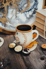 Small chocolate candies and cup of coffee on vintage wooden table