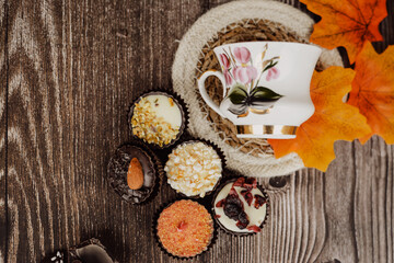 Small chocolate candies and cup of coffee on vintage wooden table