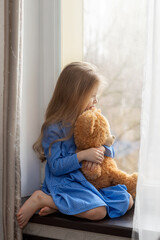 A lonely child sits on the windowsill and looks out the window. Autism concept. close-up portrait.
