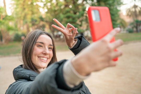 Influencer woman making a selfie blog outdoors in the park. Happy smiling lady student taking video call. Technology, education, Erasmus and communication concept. High quality photo