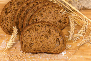 Sliced brown bread among different ears, wheat grain and flour