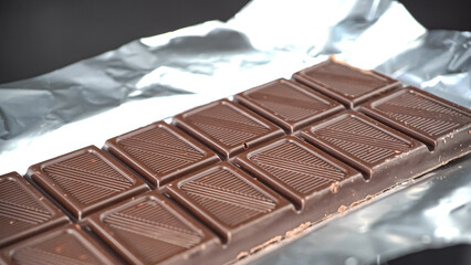 Pieces of chocolate bar in foil packaging background