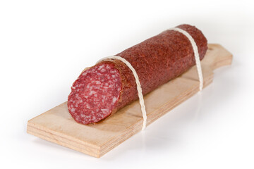 Cured sausage on cutting board on white surface close-up