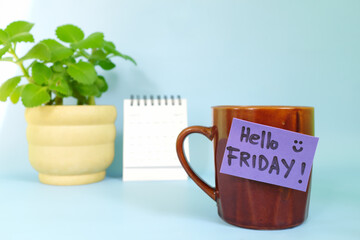 Welcome, hello and happy Friday concept. Selective focus of coffee cup with purple paper note and written message.
