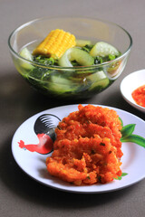 Perkedel Jagung or Bakwan Jagung, Indonesian corn fritters (made of corn, egg, flour, spring onion, pepper and salt), served with sayur bening bayam or boiled spinach clear soup on black background. 