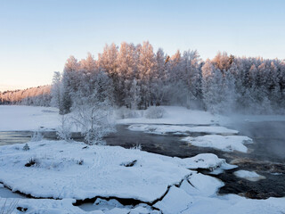Strong frost in January on the Shuya River in the Republic of Karelia, northwestern Russia.
Steam over water. The waterfall in the river is partially frozen.