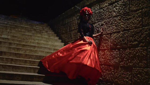 Slow motion Carnival Day of the Dead Goddess of death in complete darkness runs down the stairs.