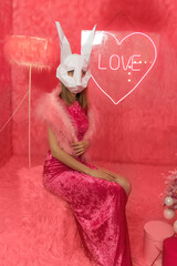 Woman in white rabbit mask closeup on the pink fur background