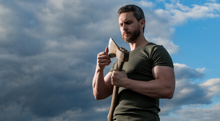 man with axe. caucasian man hold ax. brutal man on dramatic sky background. copy space