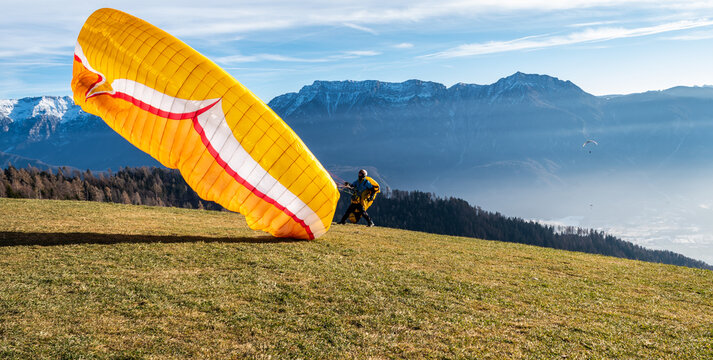 Man on a grassy slope prepare the glider for paragliding from Vetriolo Terme, Trento province - Trentino Alto Adige - Paragliding school - Italy