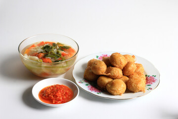 Indonesian food : Perkedel is fried patties (made of ground potatoes and minced meat), served with vegetable soup in clear bowl and chili sauce, isolated on white background