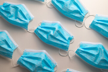 Blue surgical masks, arranged on white surface. Epidemic of covid and protection tools. 
