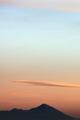 Stunning sunset with beautiful shades of orange, pink, purple and blue colors with the silhouette of a mountain range. Wallpaper, natural background with copy space.