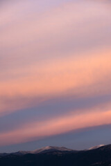Stunning sunset with beautiful shades of orange, pink, purple and blue colors with the silhouette of a mountain range. Wallpaper, natural background with copy space.