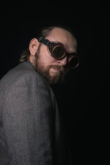 Fototapeta premium charismatic man in a classic suit and steampunk goggles on a black background stylish Portrait