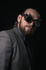 charismatic man in a classic suit and steampunk goggles on a black background stylish Portrait