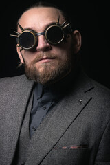charismatic man in a classic suit and steampunk goggles on a black background stylish Portrait