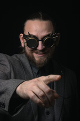 Obraz premium charismatic man in a classic suit and steampunk goggles on a black background stylish Portrait