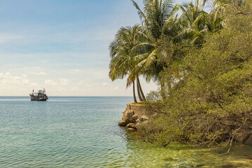 Tropical island with palm trees and boat in the sea