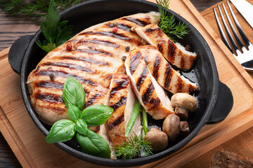 Roasted chicken fillet and mushrooms with herb in the frying pan on the wooden table close-up.