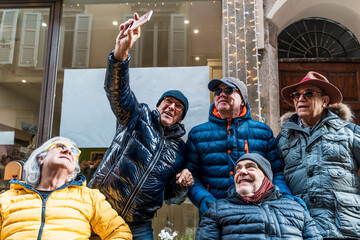 group of happy retired mature men taking a selfie with smart phone on the street