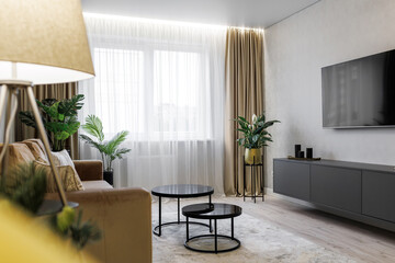 Interior design of a cozy living room with TV, armchair, coffee table and withered flowers in a vase