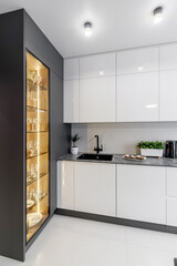 Pure empty glasses of wine in a glass window lit in a modern interior. Black and white kitchen