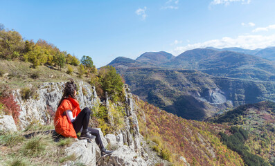 Naklejka na ściany i meble Traveler Woman sitting on a rocks in the autumn mountain . Balkan mountains, ,Bulgaria